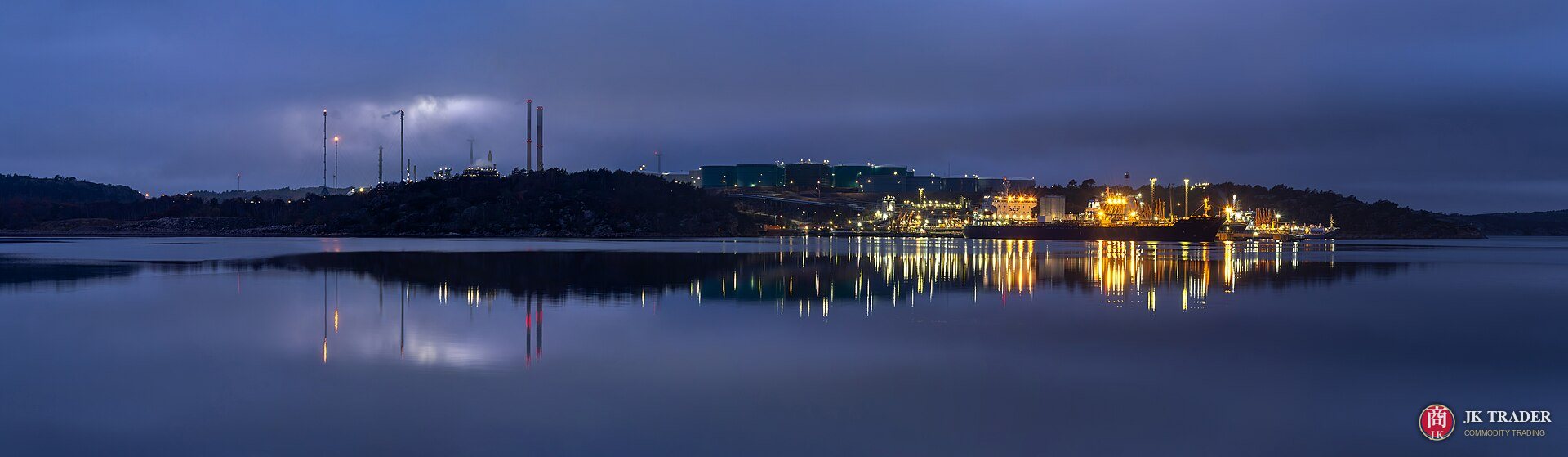 Terminal petrolera de noche con un buque tanque atracado y sus luces reflejadas en el agua